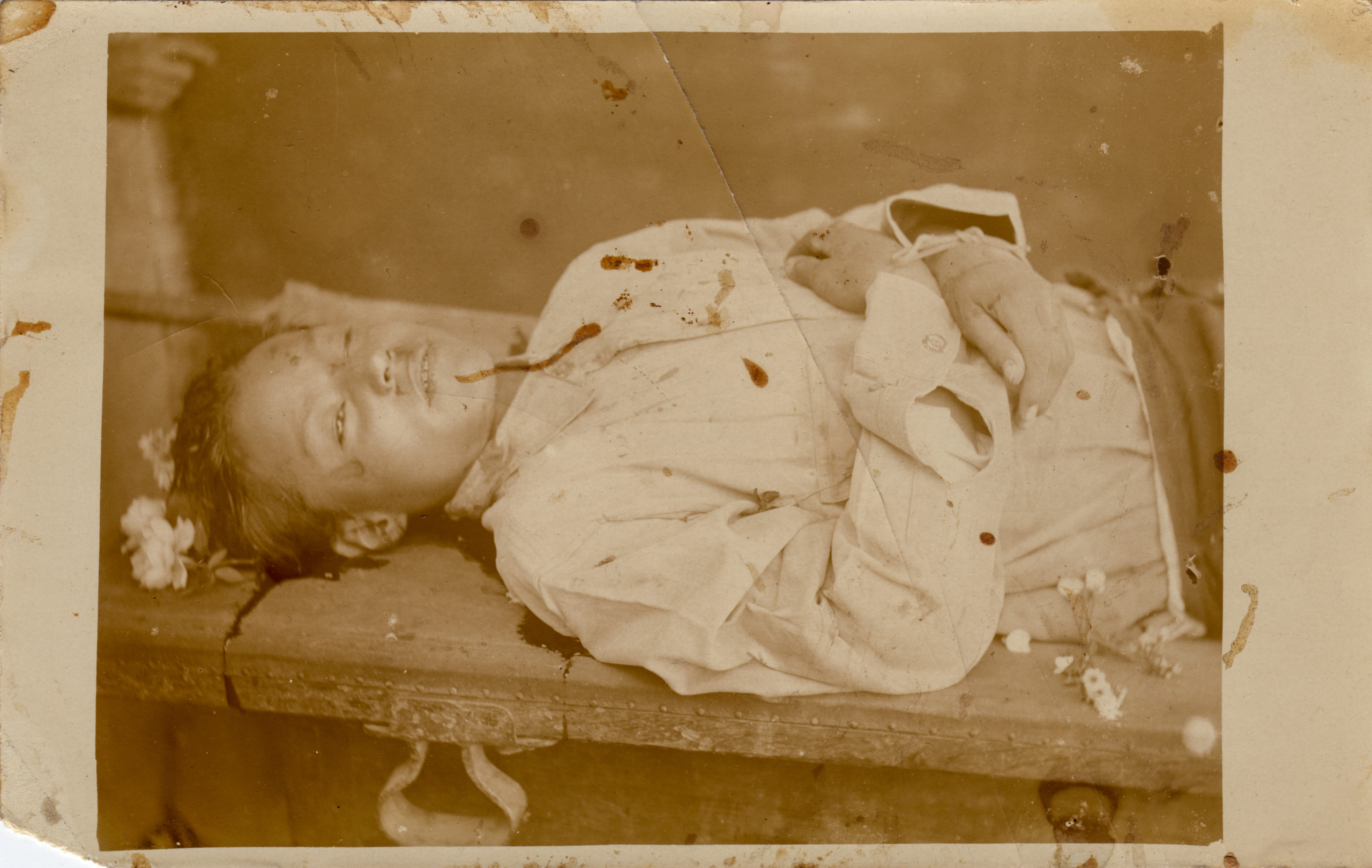 Retrato post mortem de niño recostado con ofrendas florales