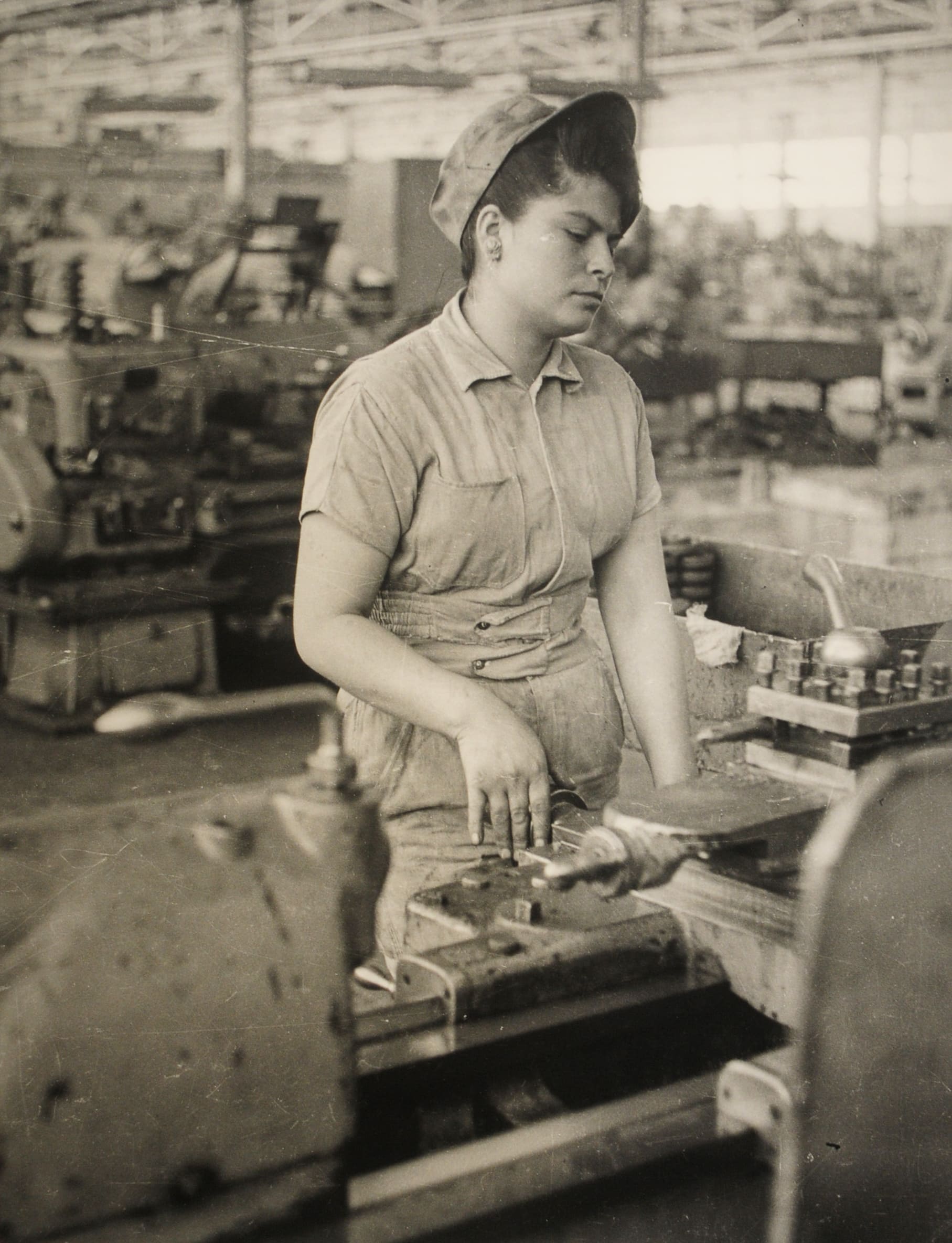 Obrera operando máquina industrial en fábrica, mediados del siglo XX
