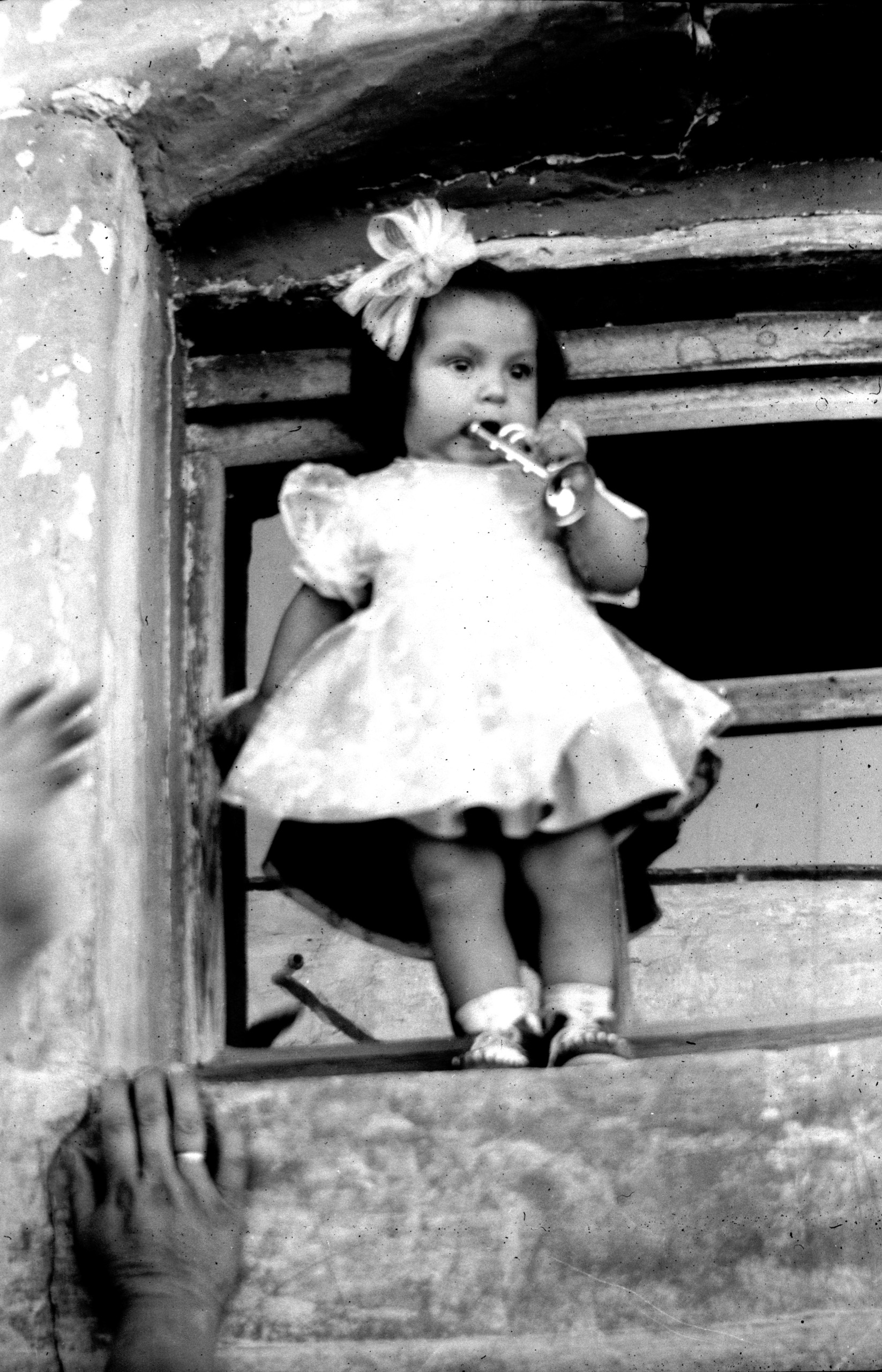 Niña con trompeta de juguete asomada a ventana en Nieves, siglo XX